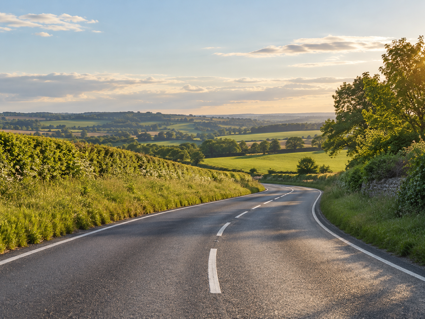 A quiet, winding road through sunlit countryside
